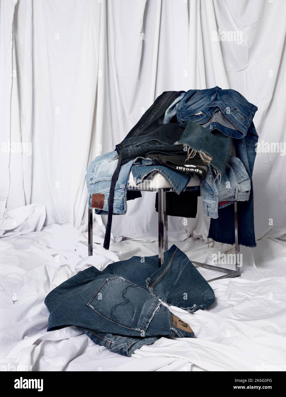 Ein Berg Jeans Hosen über dem Stuhl Stockfoto