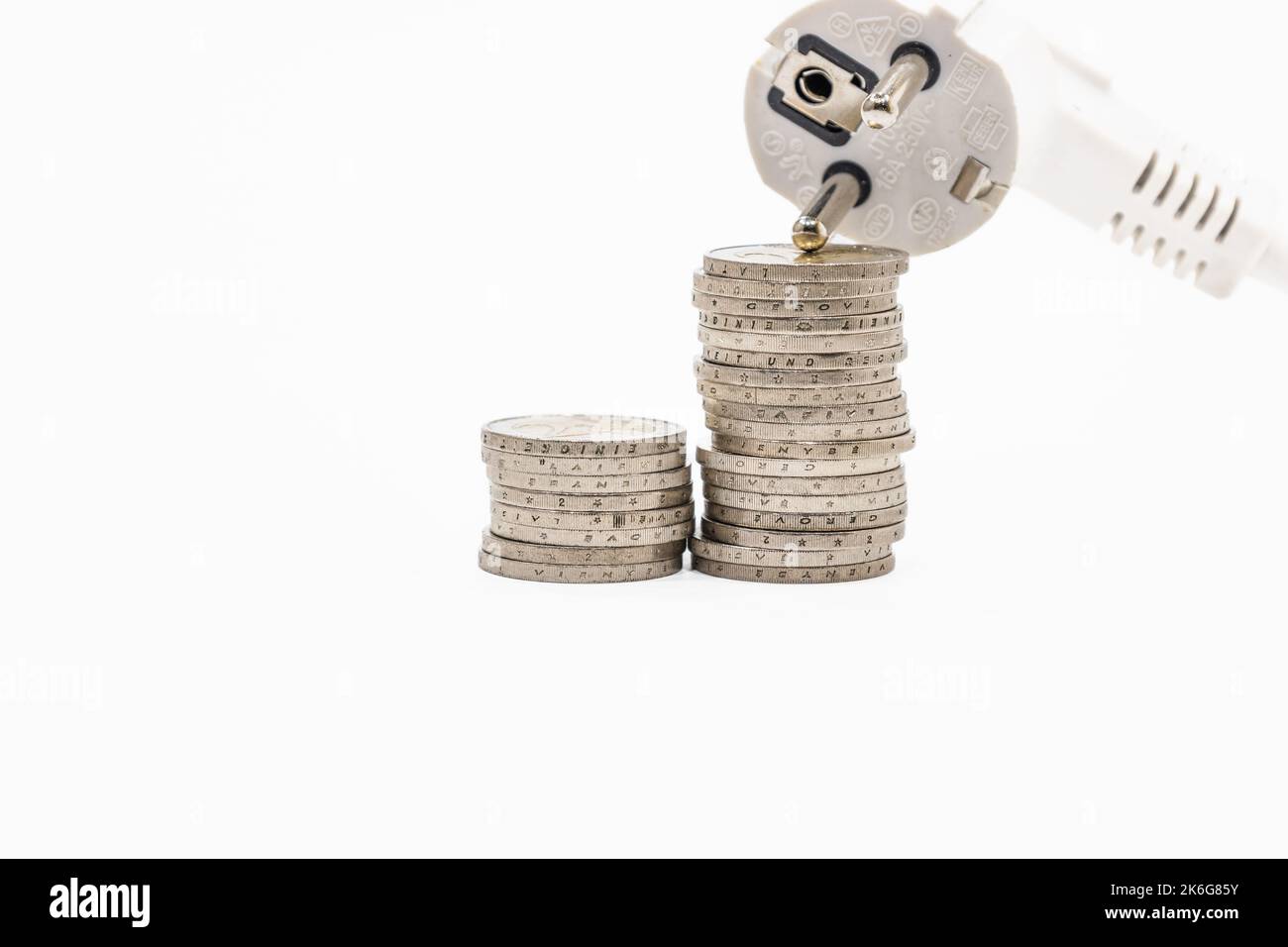 Stapel aufsteigender Münzen und elektrischer Stecker. Konzept der steigenden Strompreise Stockfoto