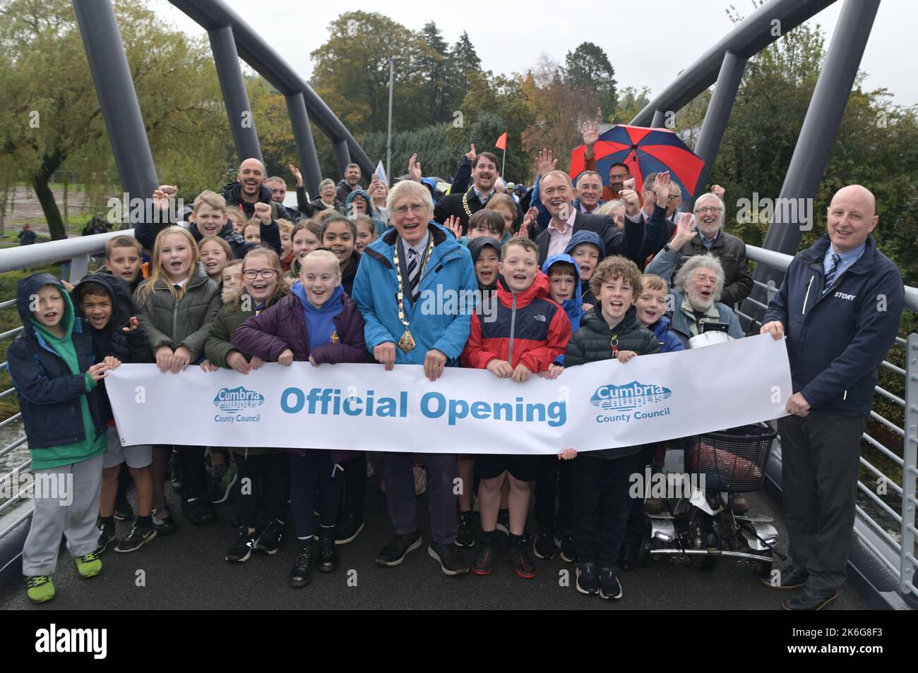 New Road, Kendal - Oktober 14. 2022 - die Gooseholme Bridge in Kendal wurde am Freitag, den 14. Oktober, vom Vorsitzenden des Cumbria County Council (CCC), Cllr Andy Connell, mit Kindern der nahegelegenen Stramongate School (alle für Fotos freigegeben) offiziell eröffnet. MP Tim Farron machte ebenfalls einen Auftritt. Die Fußgängerbrücke, die 2 Millionen Pfund kostete, ersetzte eine kleinere alte Brücke, die im Sturm Desmond beschädigt wurde, der die Stadt 2015 traf und verheerende Überschwemmungen verursachte. Die monströse Struktur wurde im Juli an ihren Platz gebracht, wobei in den letzten Monaten letzte Feinheiten vorgenommen wurden. CCC, Zusammenarbeit mit dem Auftragnehmer Story Contractin Stockfoto