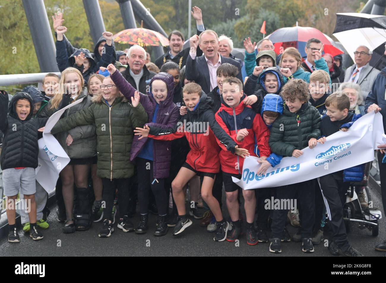 New Road, Kendal - Oktober 14. 2022 - die Gooseholme Bridge in Kendal wurde am Freitag, den 14. Oktober, vom Vorsitzenden des Cumbria County Council (CCC), Cllr Andy Connell, mit Kindern der nahegelegenen Stramongate School (alle für Fotos freigegeben) offiziell eröffnet. MP Tim Farron machte ebenfalls einen Auftritt. Die Fußgängerbrücke, die 2 Millionen Pfund kostete, ersetzte eine kleinere alte Brücke, die im Sturm Desmond beschädigt wurde, der die Stadt 2015 traf und verheerende Überschwemmungen verursachte. Die monströse Struktur wurde im Juli an ihren Platz gebracht, wobei in den letzten Monaten letzte Feinheiten vorgenommen wurden. CCC, Zusammenarbeit mit dem Auftragnehmer Story Contractin Stockfoto