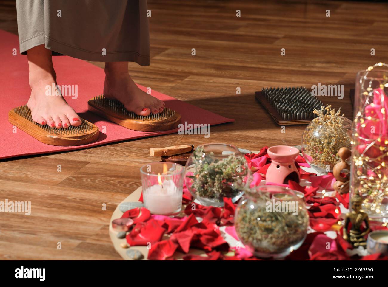 Frau, die auf dem Sadhu-Brett steht. Weibliche Füße auf Nagelbrett. Yoga, Meditation und Energiefluss üben. Stockfoto