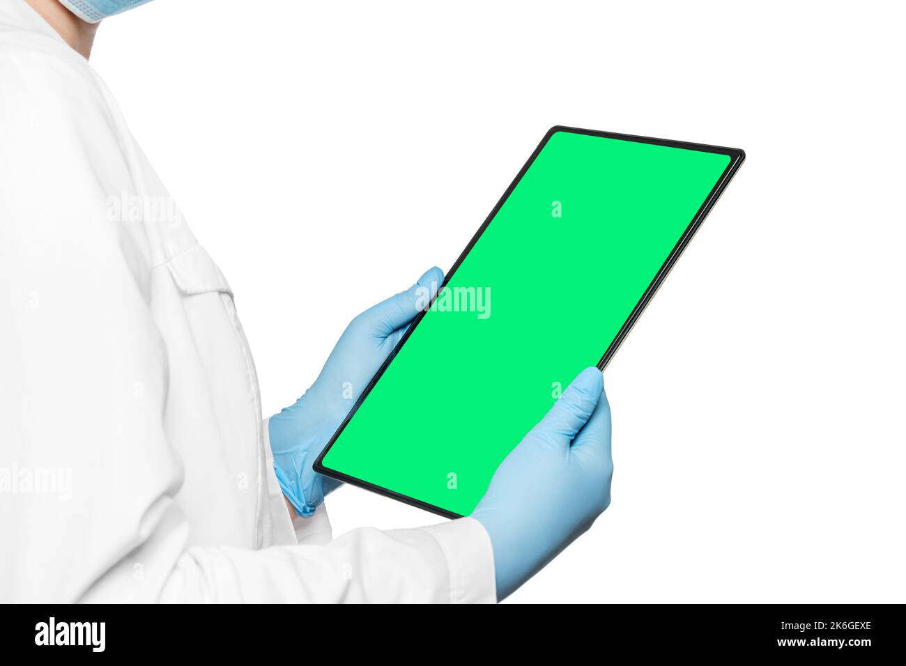 Der Arzt hält eine elektronische Tablette mit einem leeren Raum in den Händen und einem grünen Bildschirm. Stockfoto