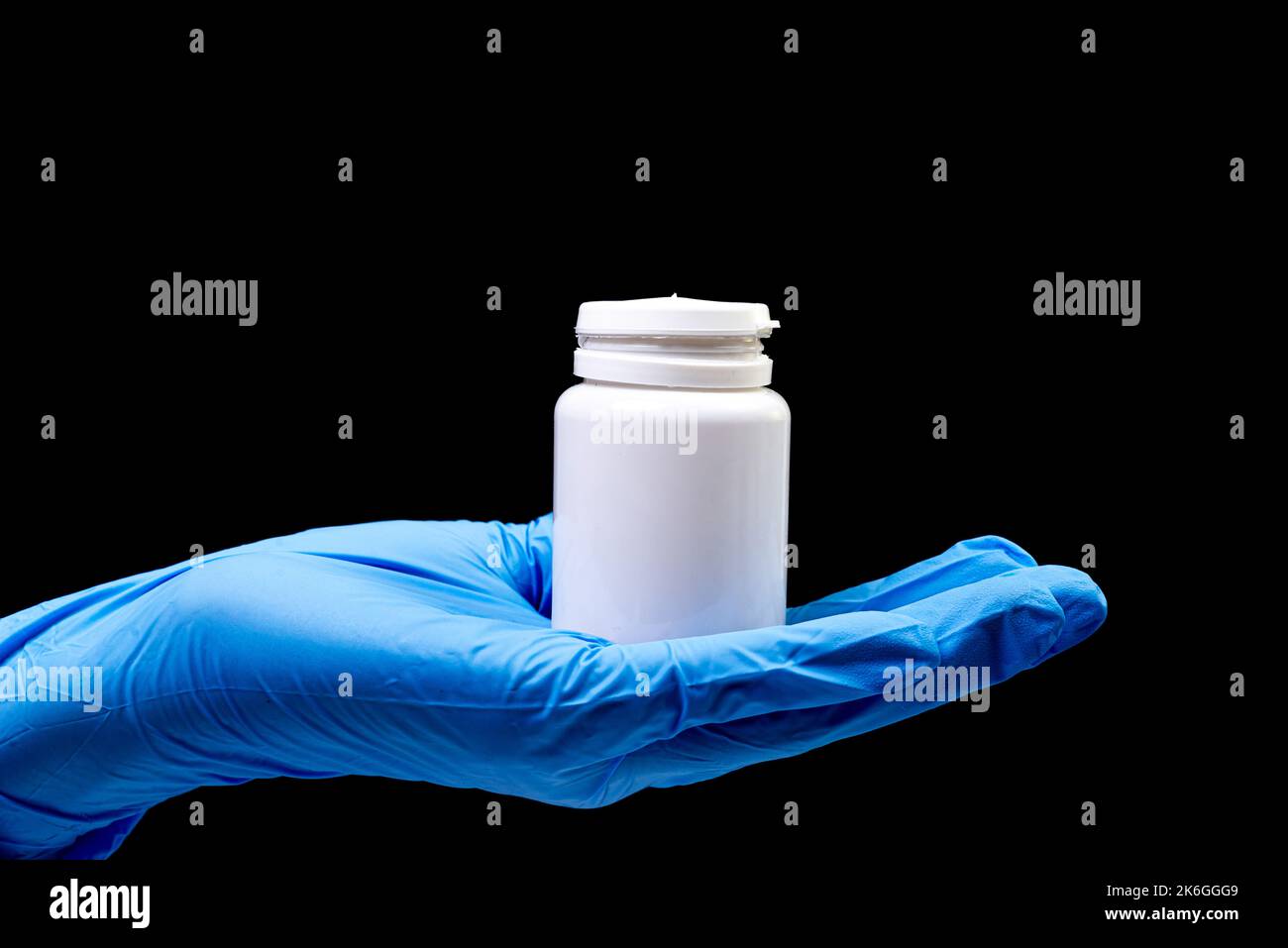 Medizinische Pillen in weißem Glas auf einem isolierten schwarzen Hintergrund mit Reflexion in der Hand natürliche Bio-Ergänzung Stockfoto
