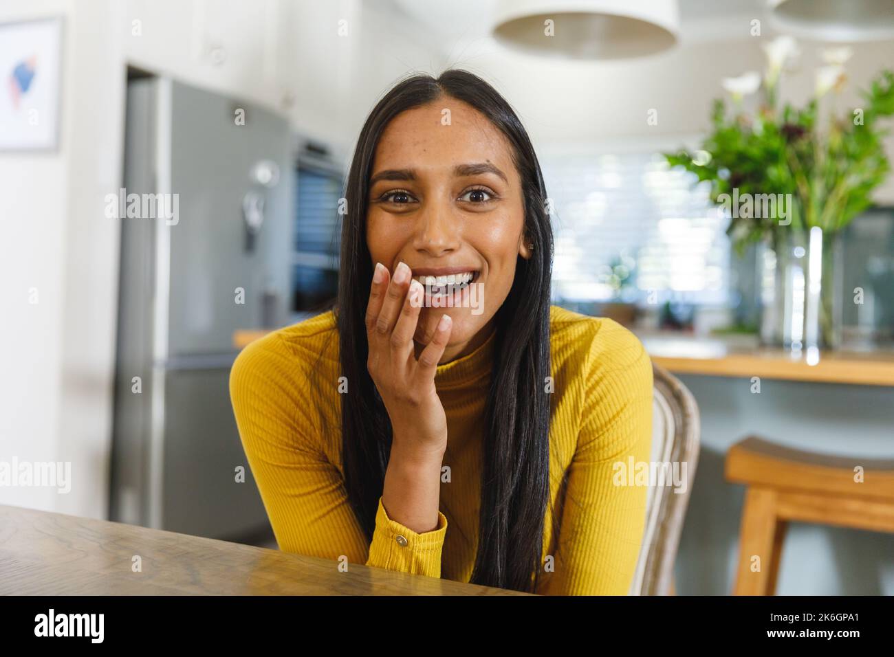 Eine glückliche, birassische Frau, die ein Lächeln auf dem Video macht und in der Küche die Kamera überrascht Stockfoto