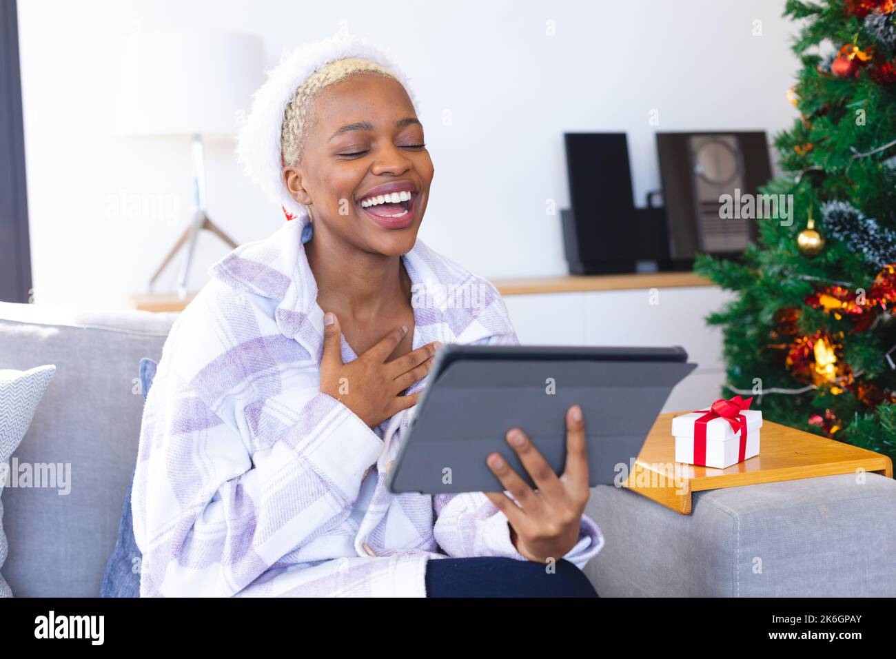Glückliche afroamerikanische Frau mit weihnachtsmann-Hut, die ein Tablet für Videoanrufe benutzt Stockfoto