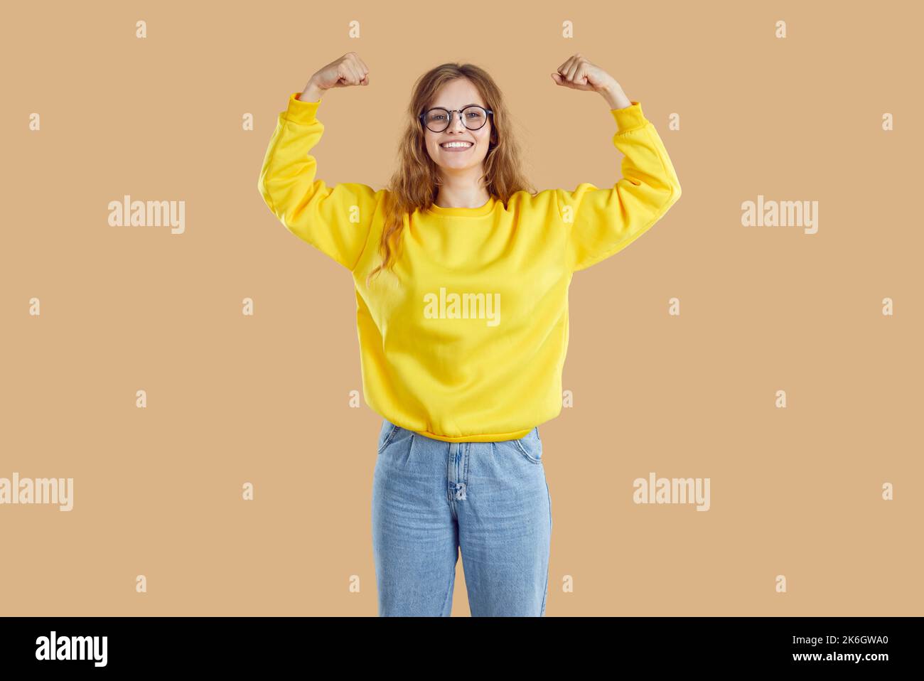 Fröhliches Teenager-Mädchen zeigt ihren Bizeps auf lustige Weise als Zeichen ihrer Stärke, ihres Erfolgs und ihrer Gesundheit. Stockfoto