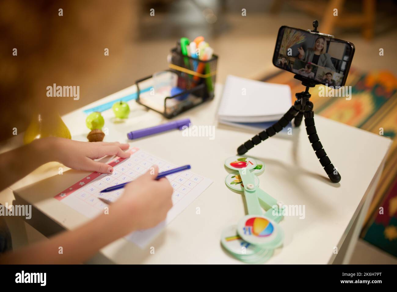 Nettes kleines elementares Schulmädchen, das online studiert und auf dem Smartphone eine Videostunde sucht. Kinder zu Hause Aktivität, Kreativität und Fernbildung Stockfoto