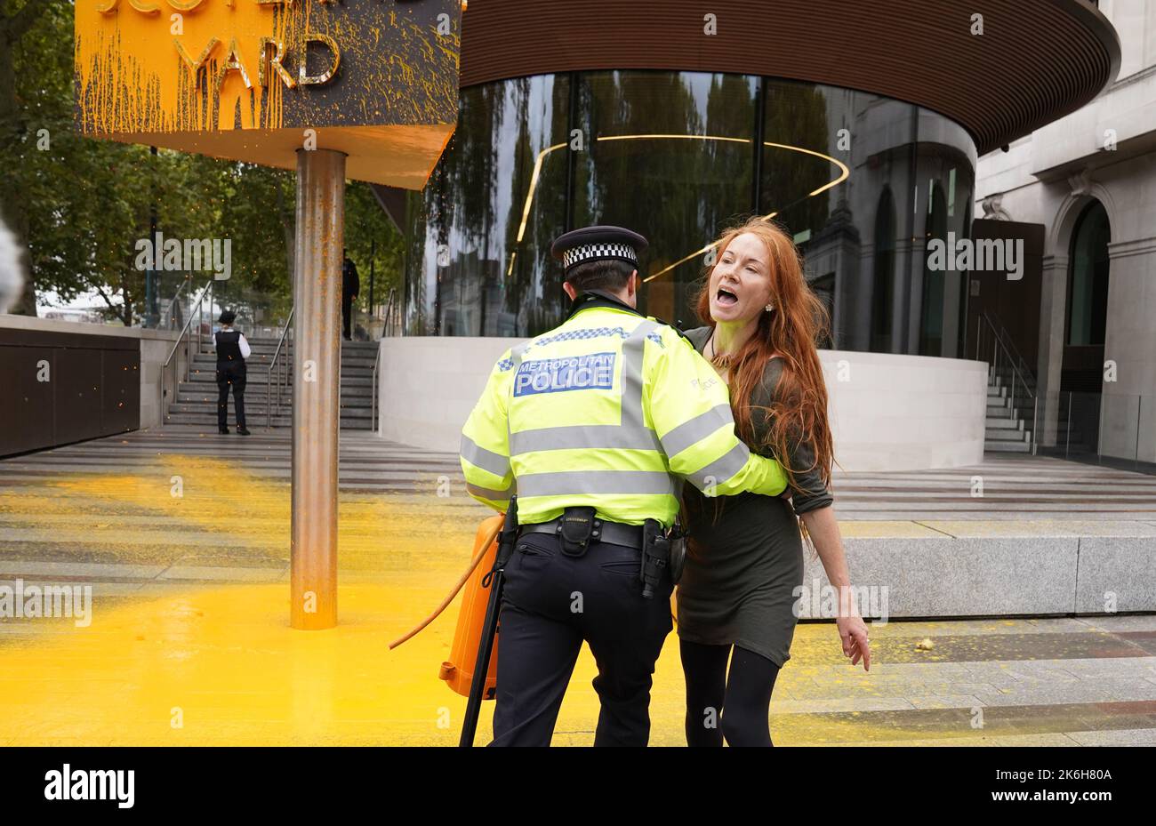 Polizisten verhaften einen Protestierenden von Just Stop Oil, nachdem sie vor dem New Scotland Yard in London ein Schild mit Sprühnebel besprüht hatte. Bilddatum: Freitag, 14. Oktober 2022. Stockfoto