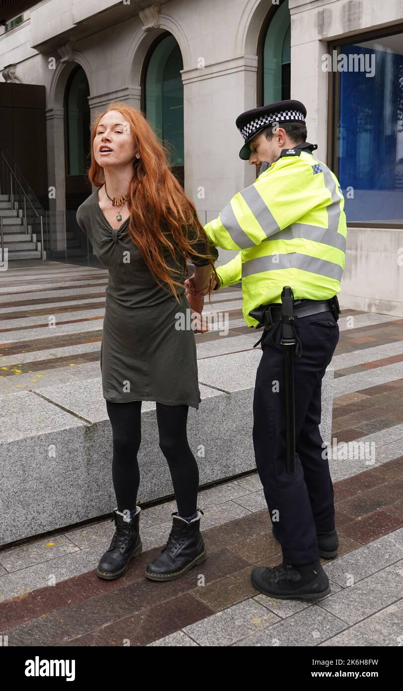Polizisten verhaften einen Protestierenden von Just Stop Oil, nachdem sie vor dem New Scotland Yard in London ein Schild mit Sprühnebel besprüht hatte. Bilddatum: Freitag, 14. Oktober 2022. Stockfoto