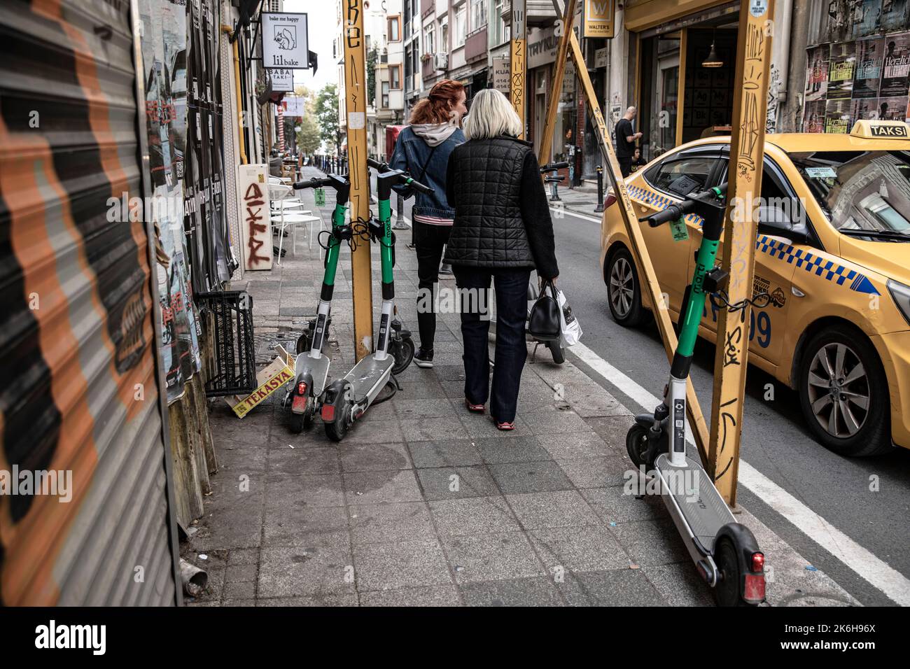 Istanbul, Türkei. 14. Oktober 2022. Fußgänger laufen an Motorroller vorbei, die entlang der Straßen in Istanbul Kadikoy geparkt sind. Elektroroller, die mit Handy-Anwendungen verwendet werden, sind in den letzten Jahren sehr beliebt geworden, um in der Stadt zu pendeln, aber sie werden oft unregelmäßig an den Straßenrändern und auf den Straßen von Istanbul geparkt, was Fußgängern das Gehen erschwert. Kredit: SOPA Images Limited/Alamy Live Nachrichten Stockfoto