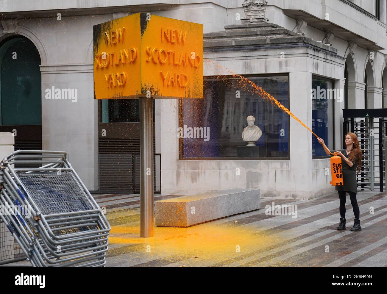 Ein „Just Stop Oil“-Spray malt ein Schild vor dem New Scotland Yard in London. Bilddatum: Freitag, 14. Oktober 2022. Stockfoto