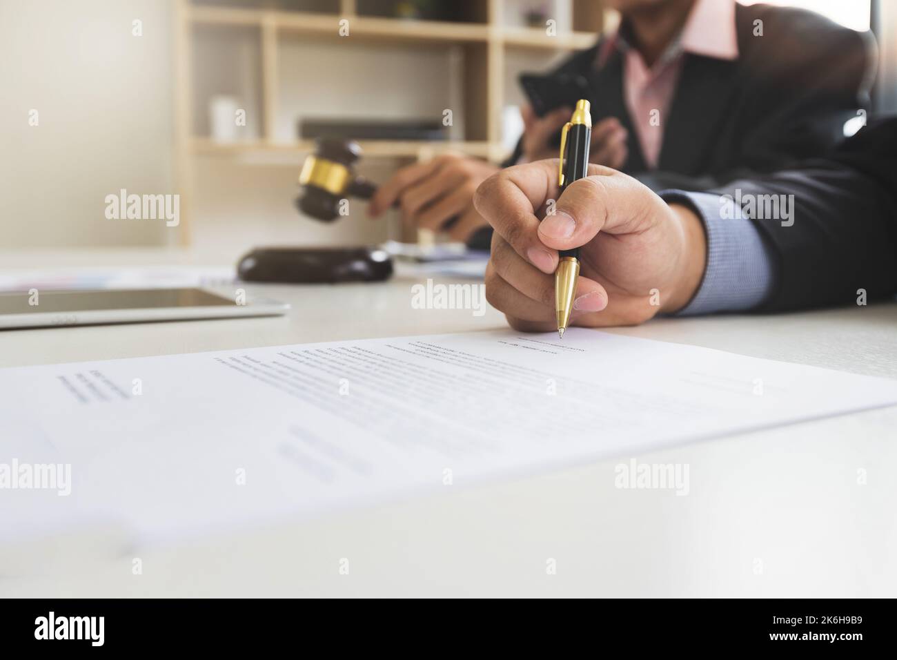 Geschäftsmann unterzeichnet einen Geschäftsvertrag mit einem Anwalt oder Rechtsberater, der neben ihm sitzt. Handelsrecht und Geschäftskooperation Konzept. Stockfoto