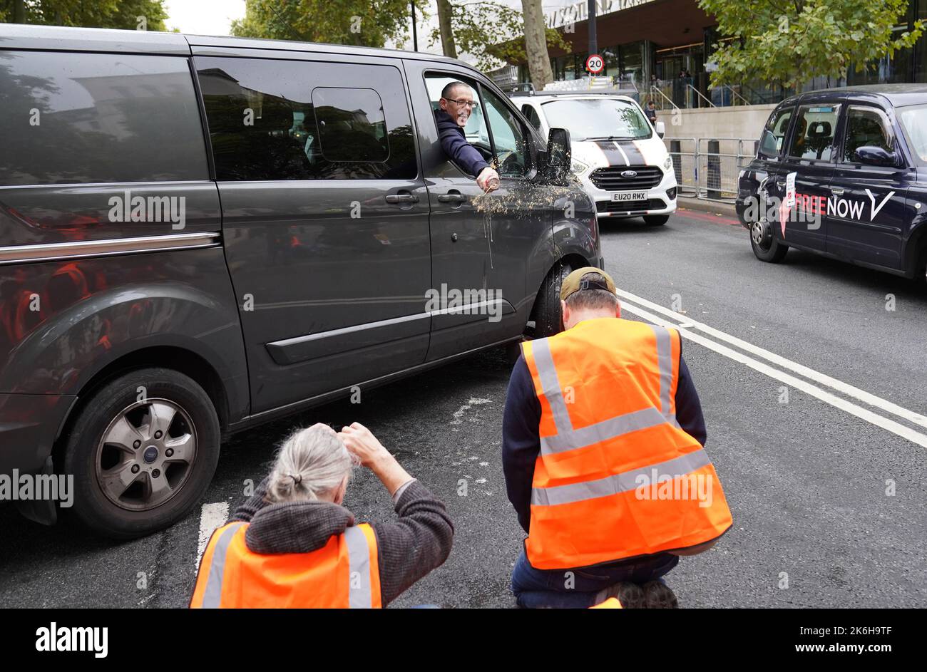 Ein Fahrer wirft einen Drink auf die Demonstranten von Just Stop Oil vor dem New Scotland Yard in London. Bilddatum: Freitag, 14. Oktober 2022. Stockfoto