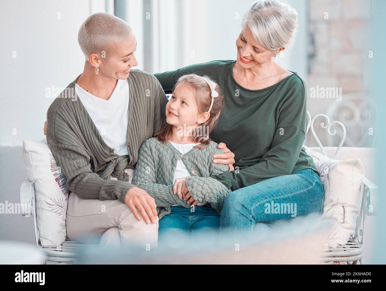 Drei Generationen von Frauen sitzen zusammen und schauen sich gegenseitig an. Liebenswert kleines Mädchen Bonding mit ihrer Mutter und Großmutter zu Hause Stockfoto