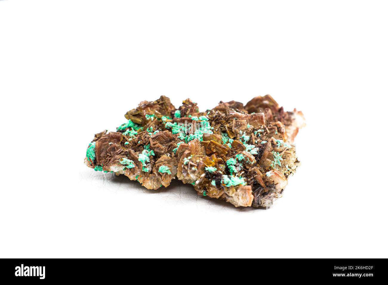 Echter brauner Albit-Kristallhaufen mit kleinen hellgrünen Malachit-Clustern, isoliert auf Weiß. Makro Stockfoto