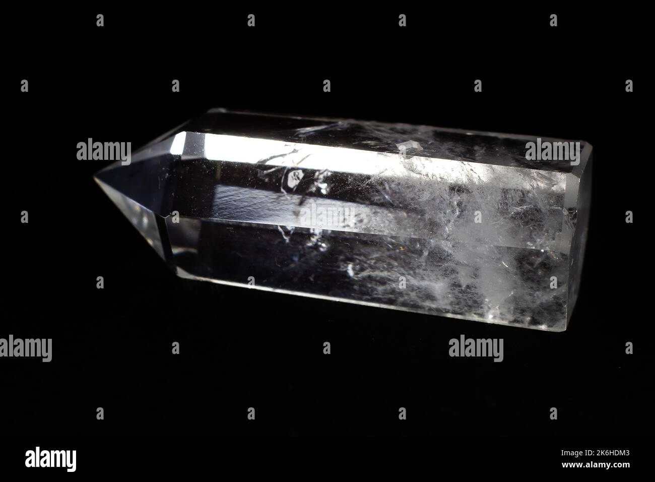 Echtes, auf schwarzer Oberfläche isoliertes Makro mit Quarzpunkt aus klarem Kristall Stockfoto