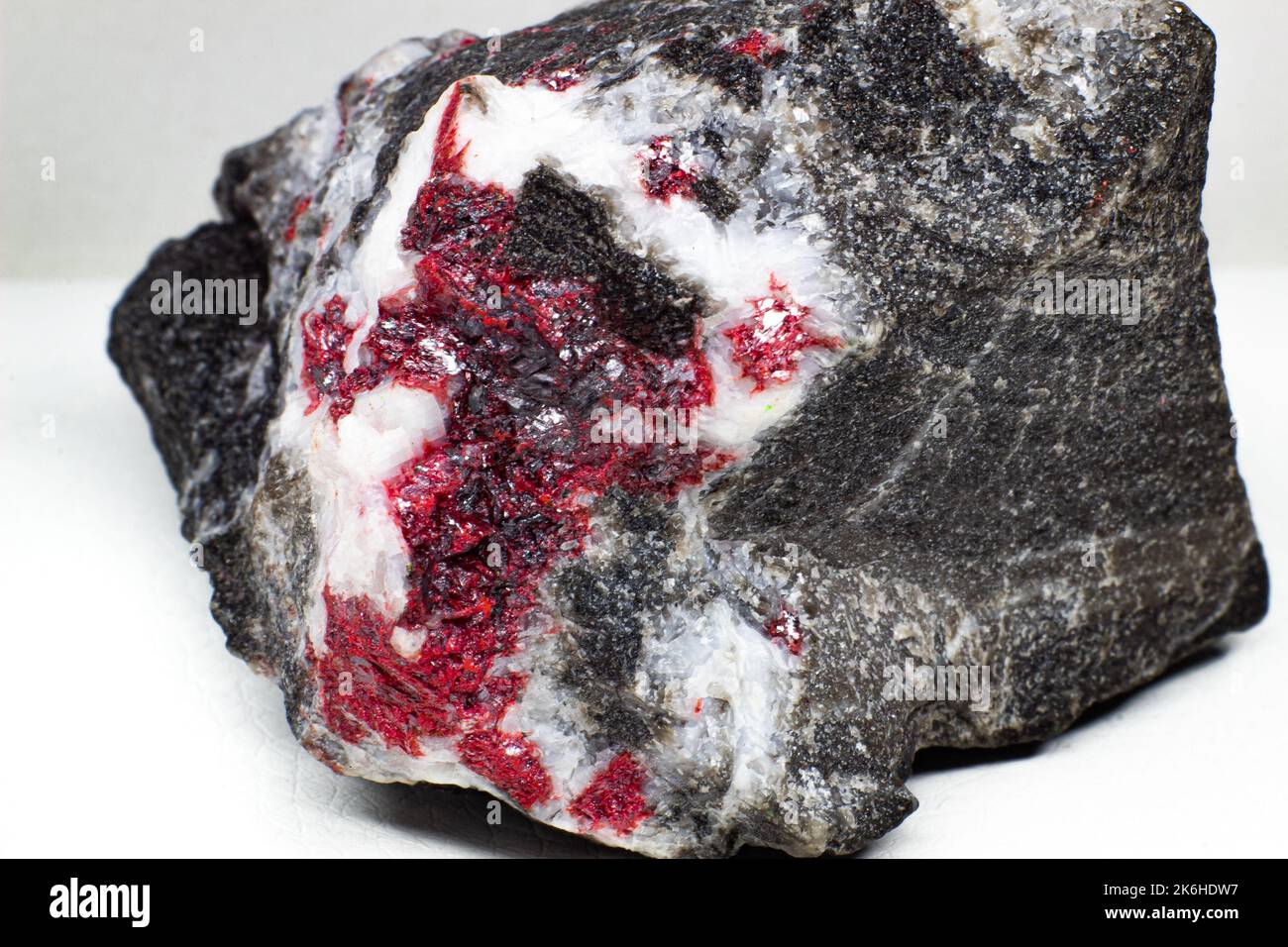 Echtes rohes rotes Cinnabar-Steinblock-Makro auf schwarzer Oberfläche isoliert Stockfoto