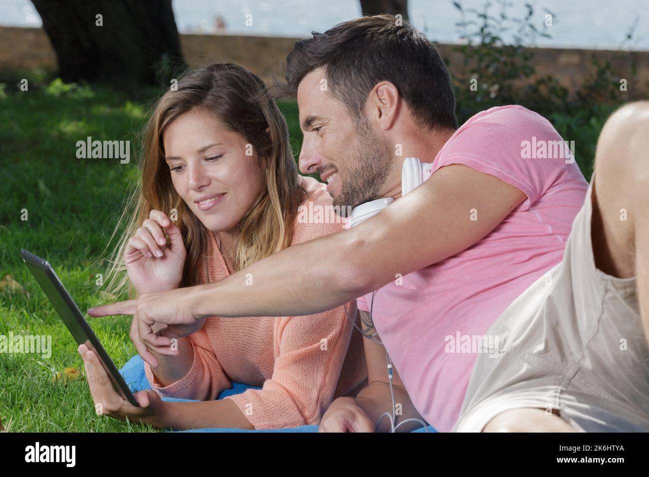 Junge schöne glückliche Paar mit digitalen Tablet im Park Stockfoto