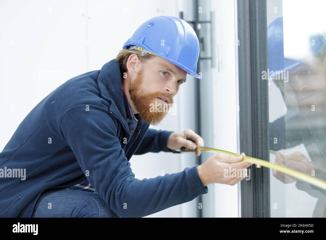 Mann, der eine Glastür misst Stockfoto