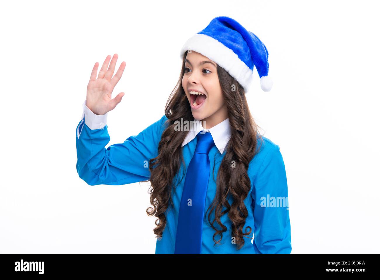 Aufgeregtes Gesicht. Frohe Weihnachten und Neujahr. Teenager-Mädchen in einem Weihnachtsmann-Hut und blauem Hemd. Weihnachtsurlaub für Kinder. Emotionaler Gesichtsausdruck. Weihnachten Stockfoto