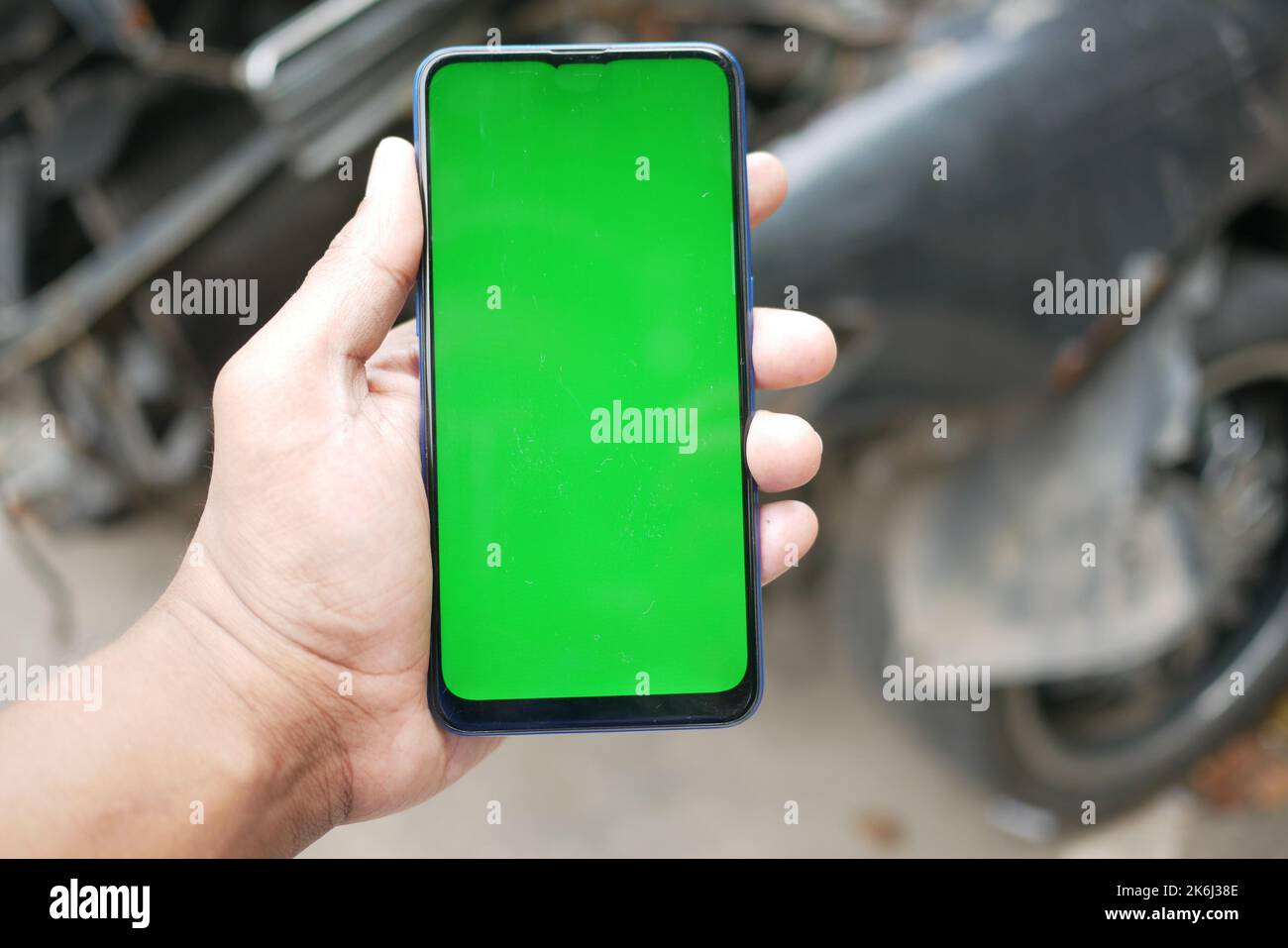 Mann, der ein Smartphone mit grünem Bildschirm für den Autoservice verwendet Stockfoto