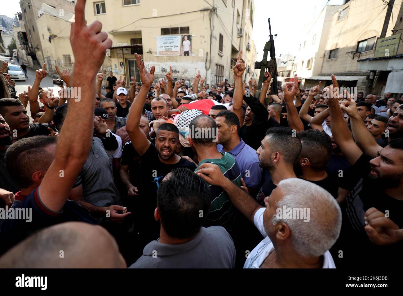 Jenin. 14. Oktober 2022. Trauernde tragen die Leiche eines palästinensischen Arztes, der von israelischen Soldaten während seiner Beerdigung in der Stadt Jenin im Westjordanland am 14. Oktober 2022 getötet wurde. Der palästinensische Arzt, der am Freitag bei Zusammenstößen zwischen Palästinensern und israelischen Soldaten in der nordwestlichen Uferstadt Dschenin von israelischen Soldaten schwer verletzt wurde, starb an seinen Verletzungen, teilte das palästinensische Gesundheitsministerium mit. Quelle: Ayman Nobani/Xinhua/Alamy Live News Stockfoto