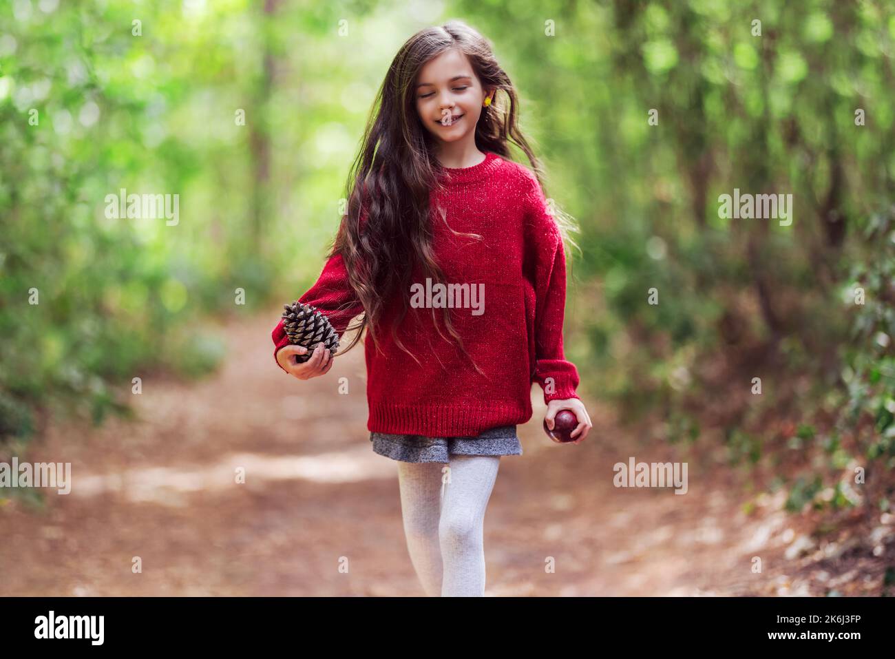 Lächelnd glücklich kleines Mädchen und Herbst großen Kiefernzackentürme in den Händen genießen Herbst in wilden Farben herbstlichen Wald. Happy Childhood Konzept Stockfoto