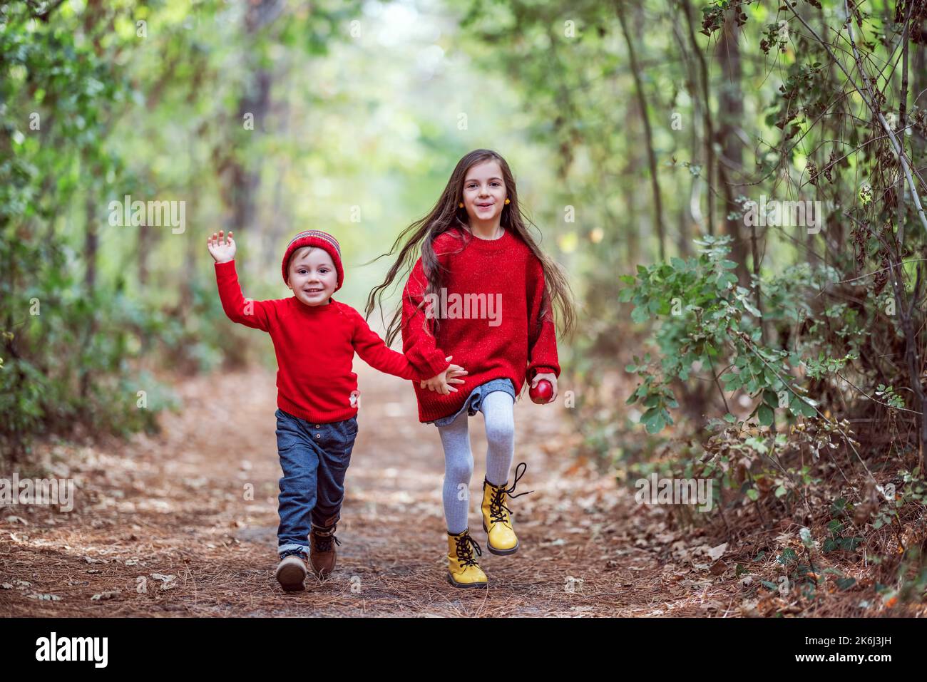 Glückliche Kinder im Wald genießen die Herbstsaison. Familie von Mädchen und Jungen, Bruder und Schwester spielen im Freien mit bunten Blätter fallen in Herbstwäldern. Stockfoto