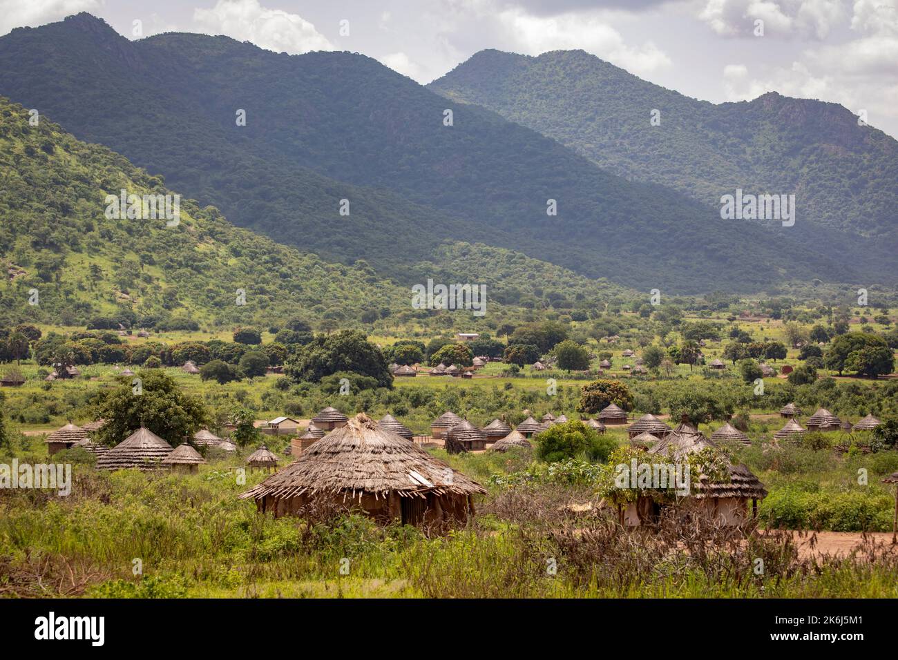 Wunderschöne Grasstrohschlammhäuser liegen in einem Tal unter den Hügeln und Bergen des Distrikts Abim, Uganda, Ostafrika. Stockfoto