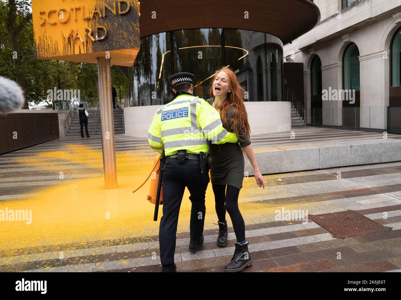 Ein „Just Stop Oil“-Protestler wird von der Polizei weggeführt, nachdem er ein Schild vor dem New Scotland Yard in London besprüht hat. Bilddatum: Freitag, 14. Oktober 2022. Stockfoto