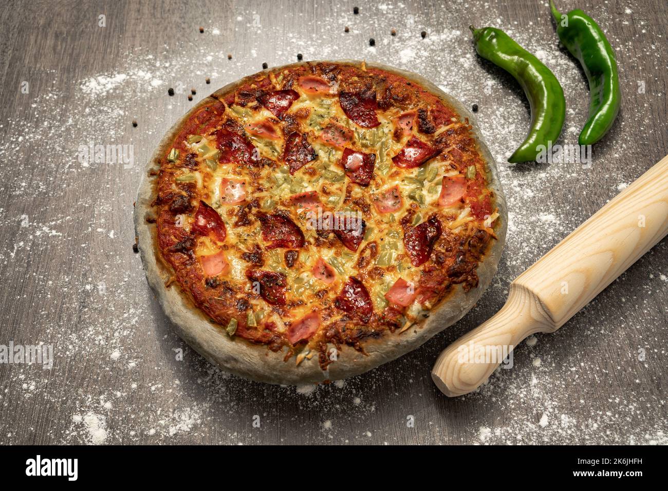Gebackene Pizza mit grauem Teig, süßem Schinken, Chorizo, grünem Pfeffer und Käse. Gesundes Essen, hausgemachte italienische Küche. Farbiger Pizzateig. Stockfoto