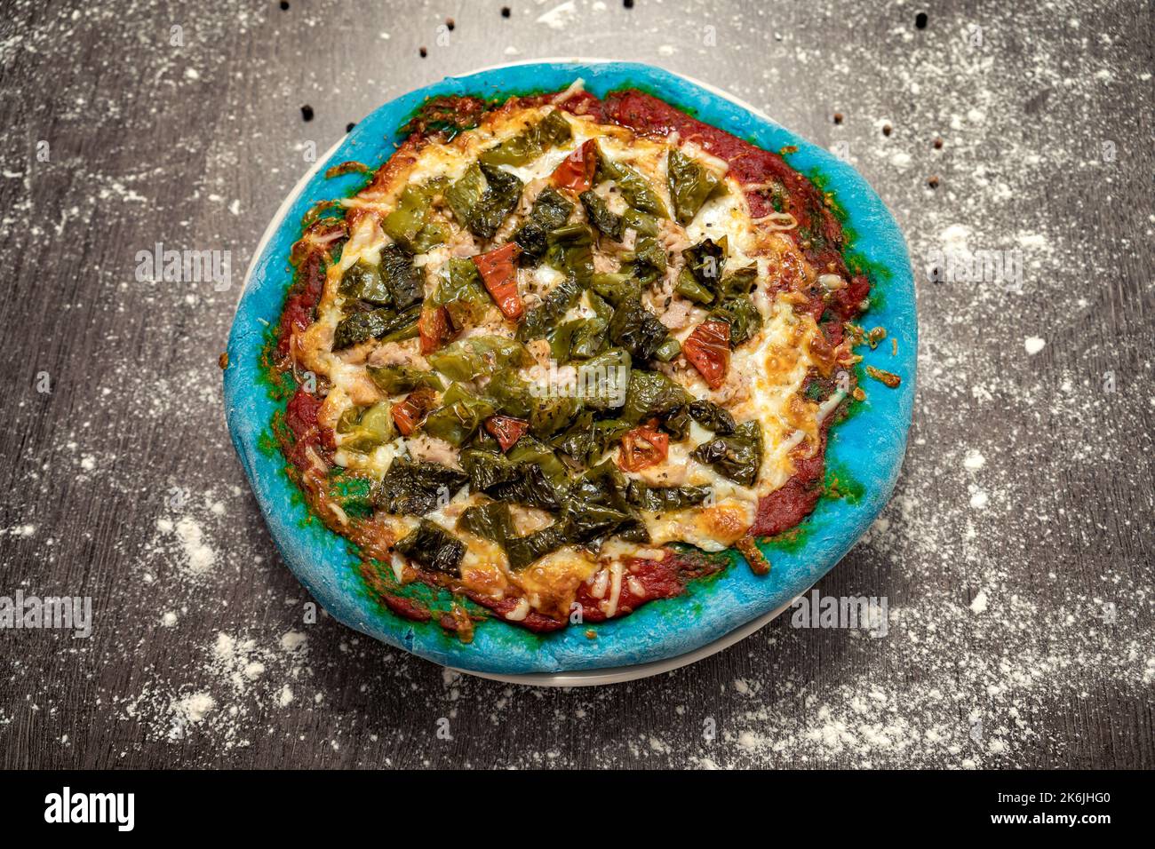 Gebackene Pizza mit Thunfisch, grünem Pfeffer und Käse und blauem Teig. Gesundes Essen, hausgemachte italienische Küche. Farbiger Pizzateig. Stockfoto