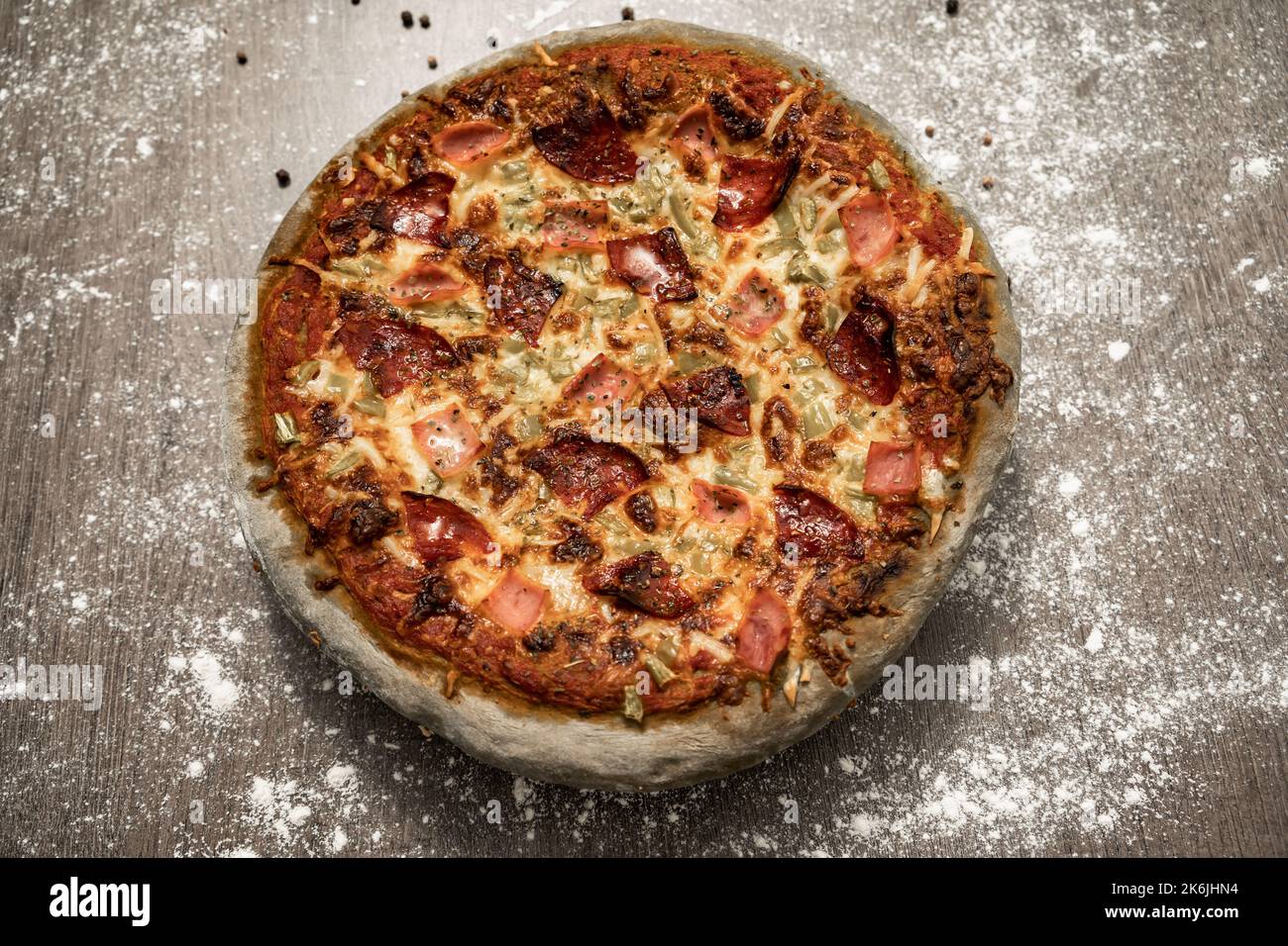 Gebackene Pizza mit grauem Teig, süßem Schinken, Chorizo, grünem Pfeffer und Käse. Gesundes Essen, hausgemachte italienische Küche. Farbiger Pizzateig. Stockfoto