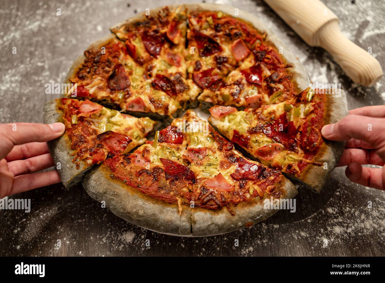 Junge Leute, die sich innovative, mit grauem Teig gebackene Pizza teilen. Gesundes Essen, hausgemachte italienische Küche. Stockfoto