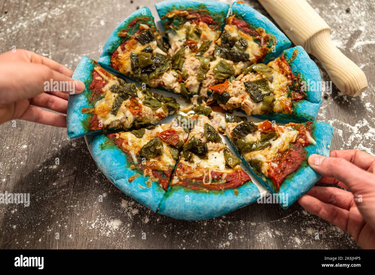 Junge Leute, die sich innovative, mit blauem Teig gebackene Pizza teilen. Gesundes Essen, hausgemachte italienische Küche. Stockfoto