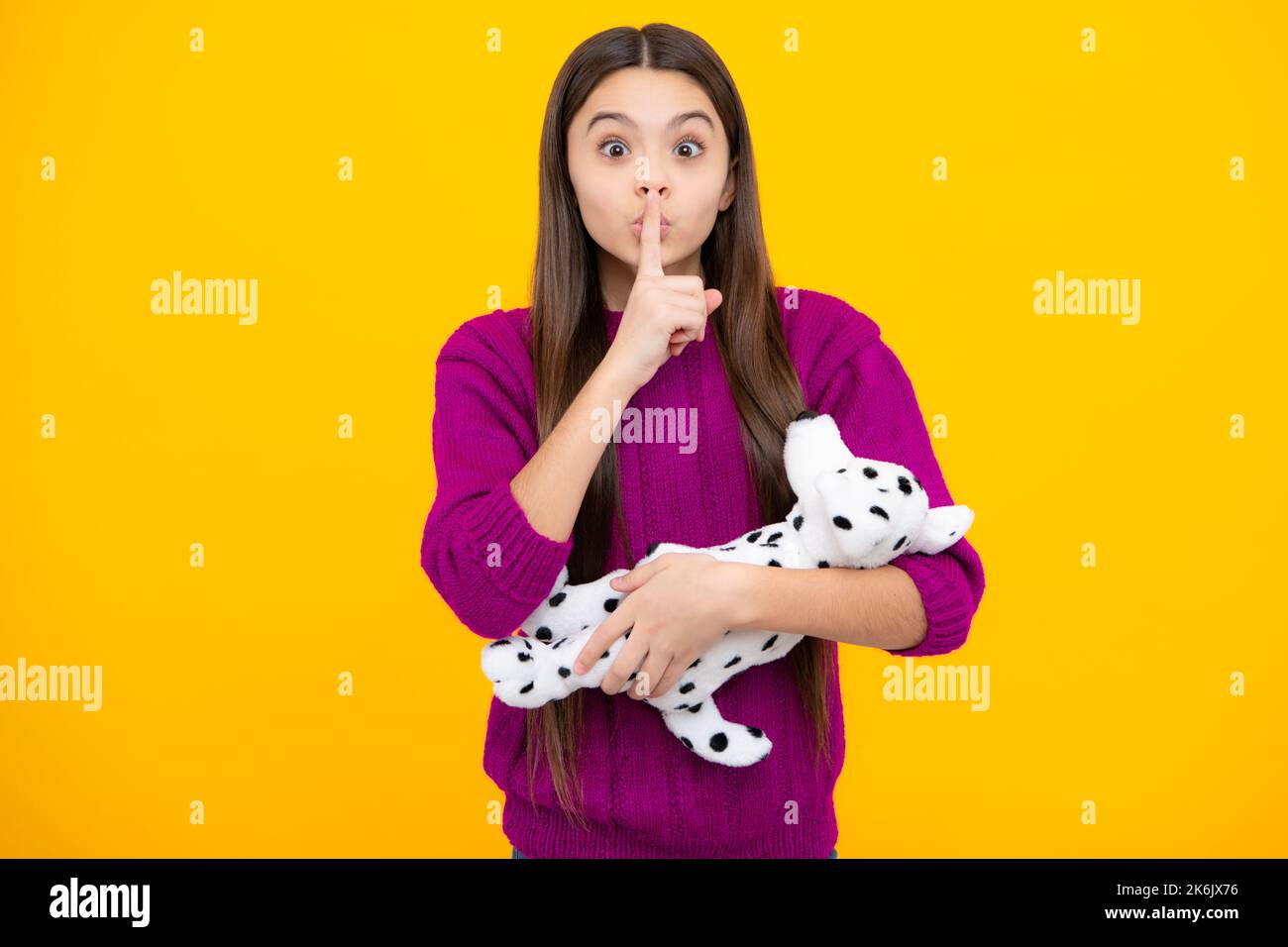 Lustiges Gesicht. Teenager Kind Mädchen in halten Plüsch Spielzeug isoliert auf gelbem Hintergrund, glückliche Kindheit. Stockfoto