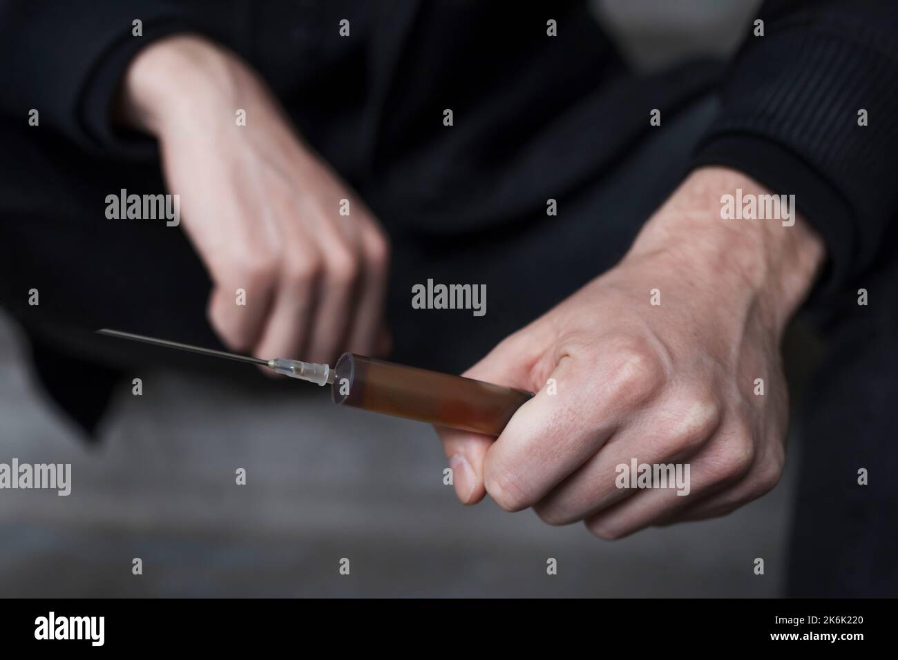 Süchtig mit einer Spritze in den Händen, Nahaufnahme. Suchtkonzept. Stockfoto