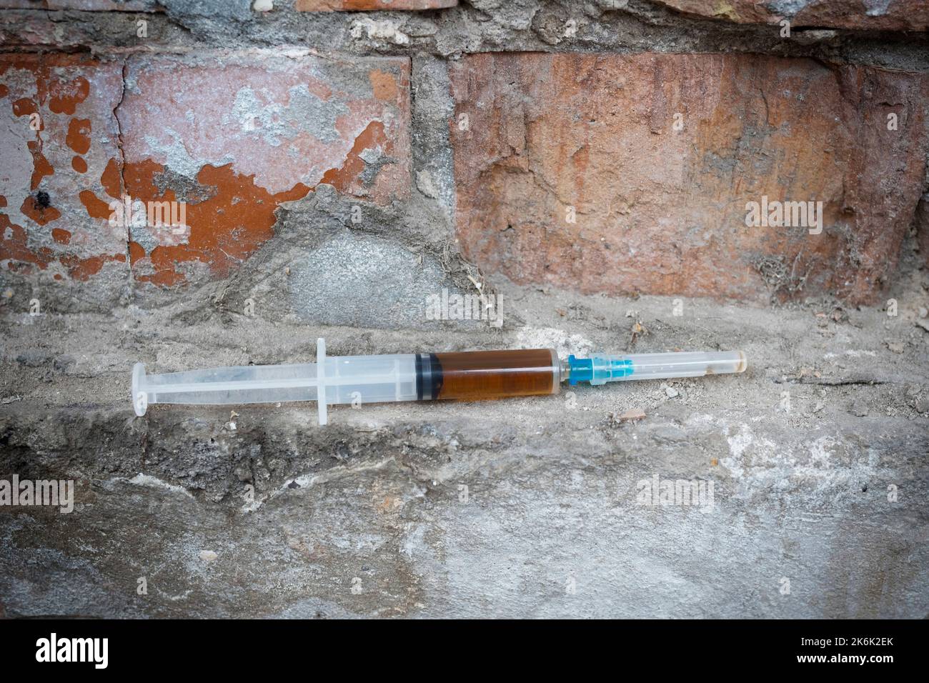 Spritze mit einer narkotischen Substanz, vor dem Hintergrund einer verlassenen Wand. Suchtkonzept. Stockfoto