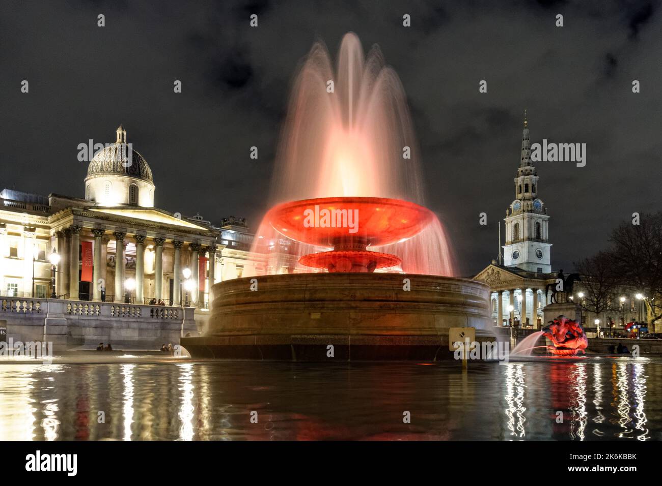 Beleuchteter Springbrunnen am Trafalgar Square bei Nacht, London England Großbritannien Stockfoto