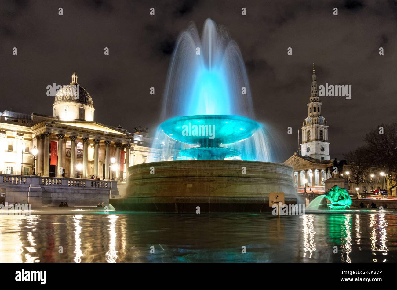 Beleuchteter Springbrunnen am Trafalgar Square bei Nacht, London England Großbritannien Stockfoto