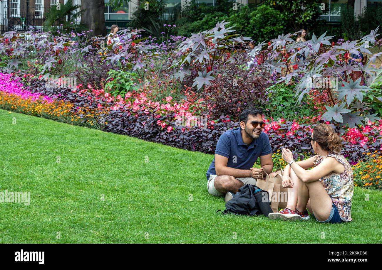 Ein Paar sitzt auf dem Gras in den Victorian Embankment Gardens London UK Stockfoto