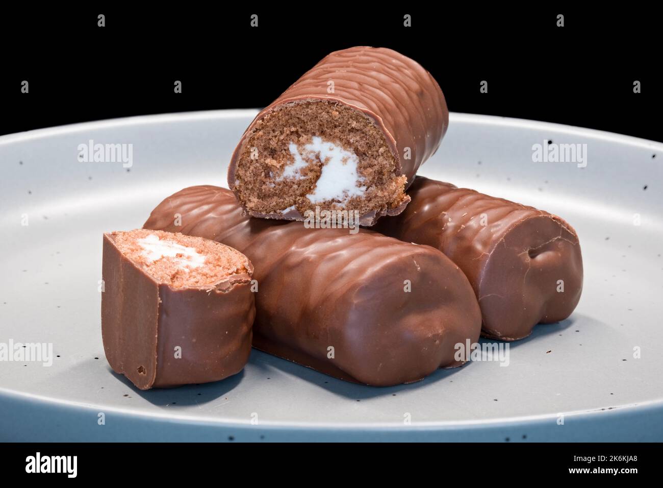 Drei Schokoladenbrötchen oder Kuchen gefüllt mit weißer Sahneeibe und fertig zum Essen. Stockfoto