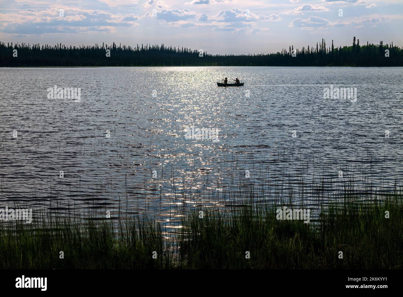 Zwei Erwachsene paddeln bei Sonnenuntergang mit dem Kanu über den Deadman Lake, den Deadman Lake Campground, das Tetlin National Wildlife Refuge, Alaska und die USA Stockfoto