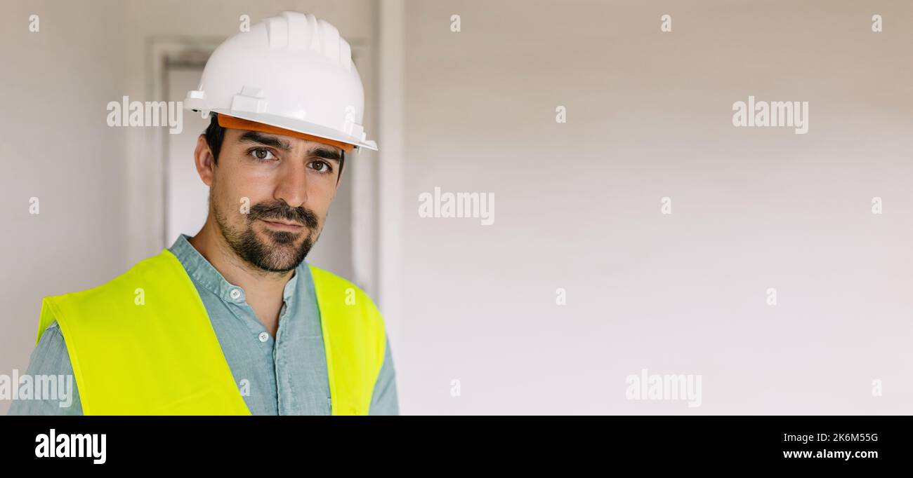 Porträt eines jungen Ingenieurs mit Schutzhelm, der in einem Gebäude steht Stockfoto