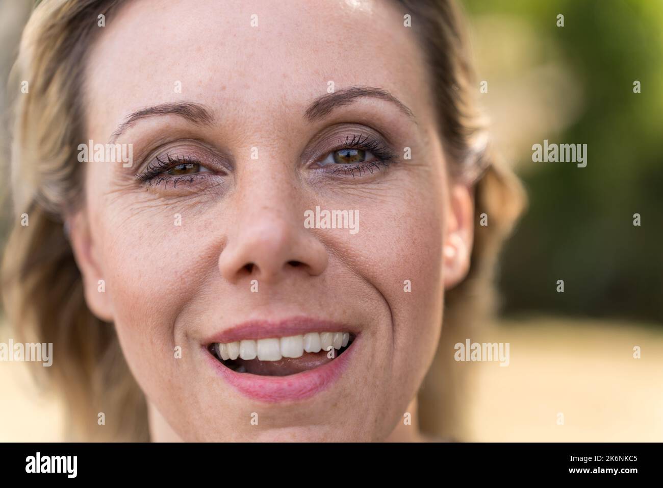 Nahaufnahme des Gesichts einer attraktiven blonden, reifen Frau in den Vierzigern, mit einem schelmischen Lächeln und einem zwinkenden Auge Stockfoto