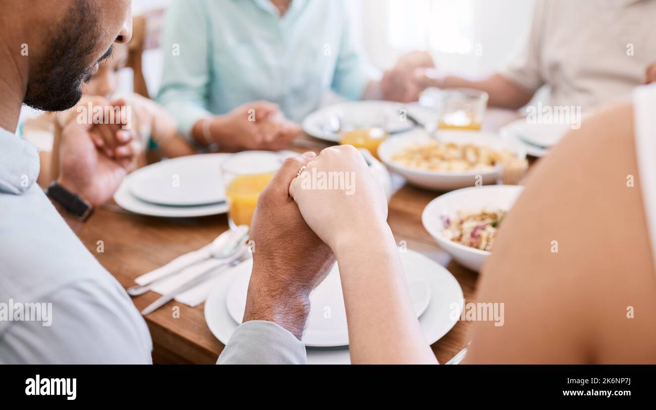 Wir bleiben zusammen, weil wir gemeinsam beten. Eine schöne Familie segnet das Essen mit einem Gebet am Tisch zusammen zu Hause. Stockfoto