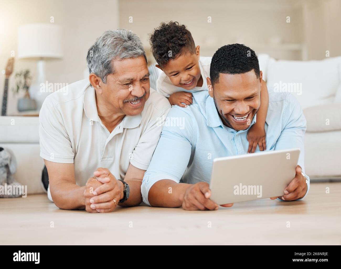 Liebe versagt nie. Ein reifer Mann lag mit seinem Sohn und seinem Enkel auf dem Boden, während er zu Hause ein Tablet benutzte. Stockfoto