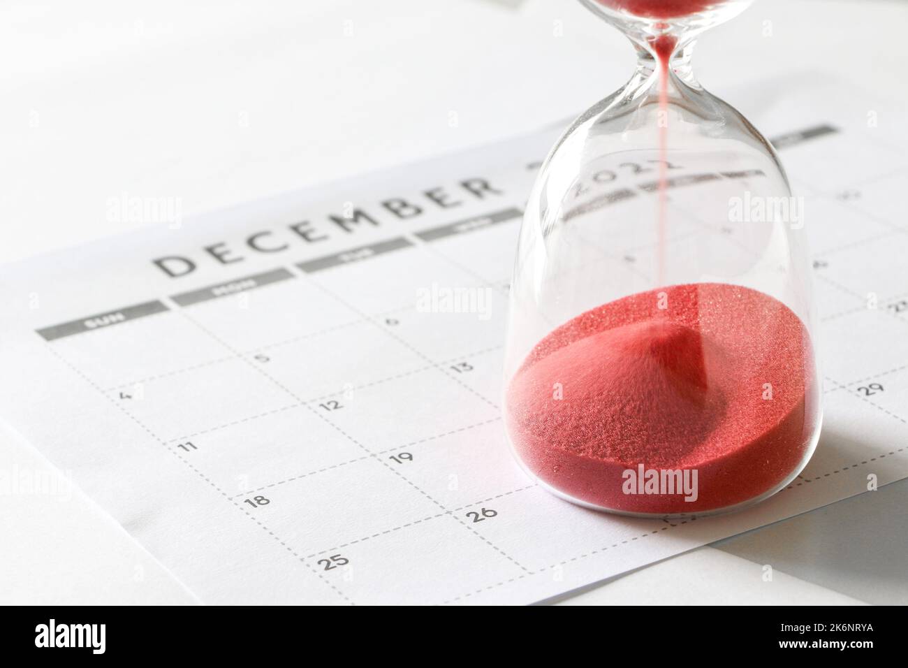 Roter Sand, der durch Sanduhr-Birnen läuft, im Dezember-Kalender, Countdown bis Weihnachten und Ende des Jahres Stockfoto