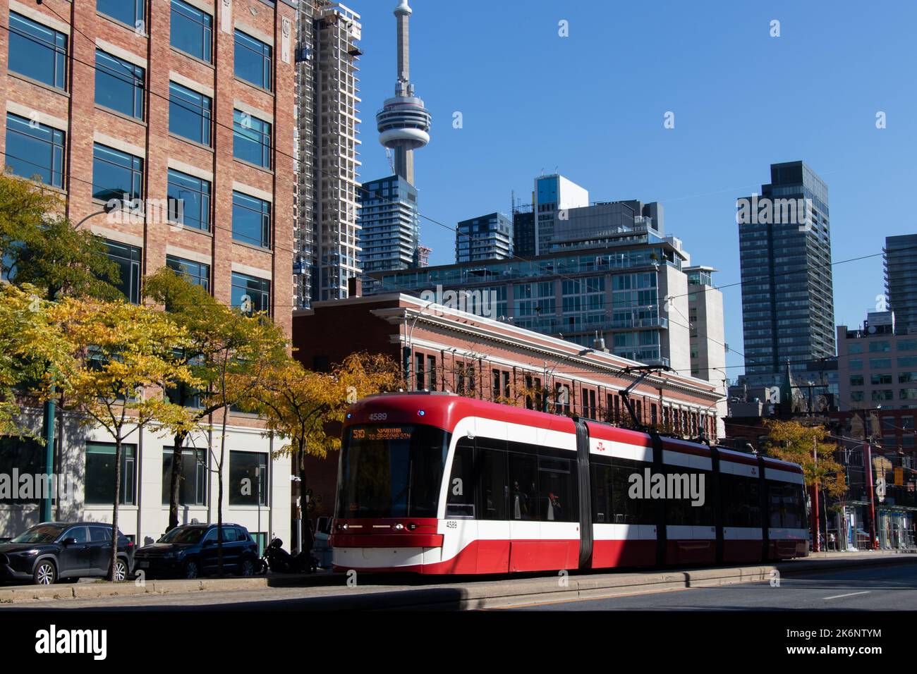Eine TTC-Straßenbahn fährt die Spadina Avenue in der Innenstadt von Toronto entlang, wobei der CN Tower im Hintergrund zu sehen ist. Im Herbst und an klaren Tagen. Stockfoto