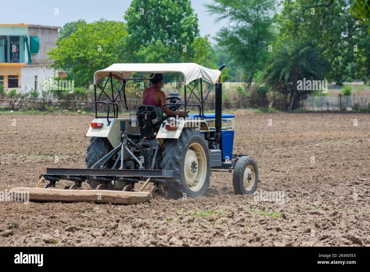 TIKAMGARH, MADHYA PRADESH, INDIEN - 04. JULI 2022: Landwirt im Traktor, der Land für die Aussaat vorbereitet. Stockfoto